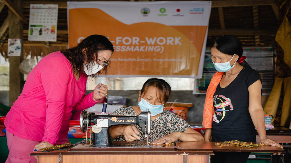 Sarah Dilangalen, Women’s Federation President of Datu Abdullah Sangki, Maguindanao supervises two women on sewing Inaul face masks.
