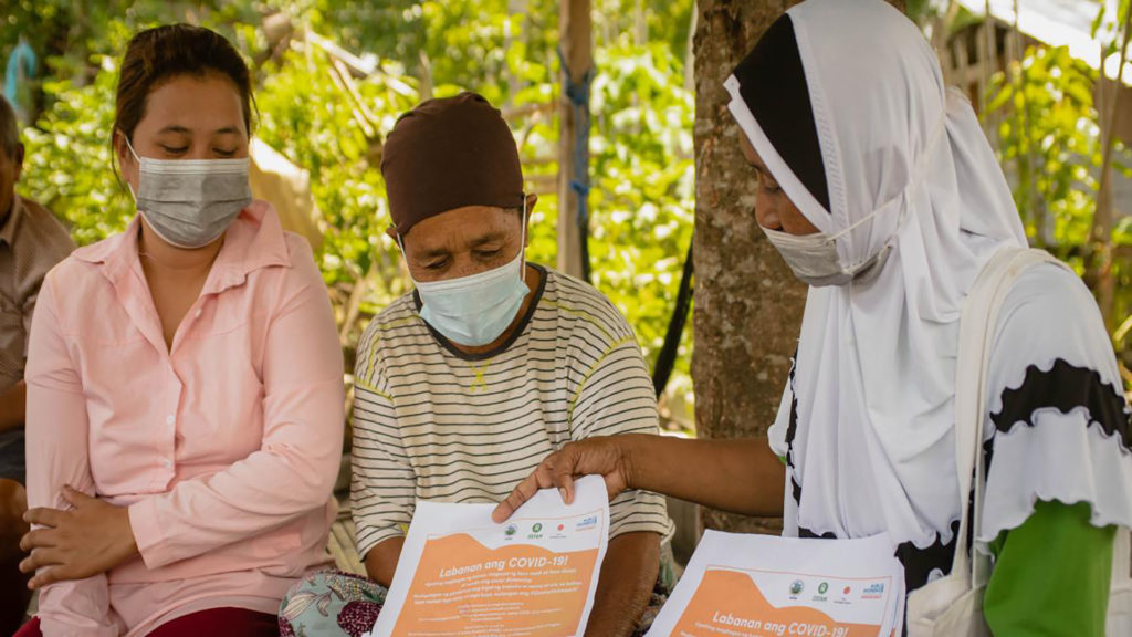 Hasna Tuwa, a local monitor and barangay health worker, explains the COVID-19 safety protocols to Datu Abdullah Sangki, Maguindanao residents. (Photo: Princess Taroza/Oxfam)