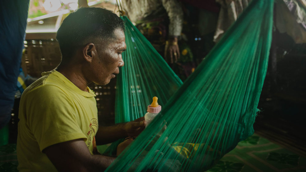 Ibrahim Mantikayan, one of the MMH champions, shows the HBCC storyboards to his two-year-old son, Datu Nursalam Mantikayan, at Sultan sa Barongis, Maguindanao.