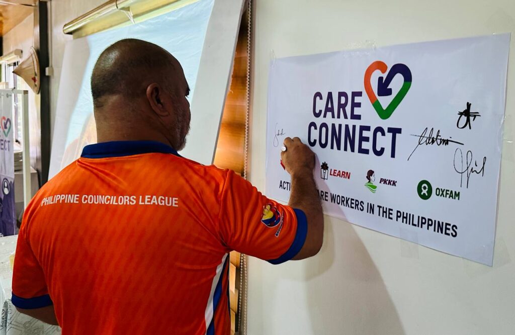 Photo of project partner signing the Care Connect logo at the Care Connect Biliran launch by Oxfam Pilipinas, PKKK, Government of Canada, and local partners. For info, visit oxfam.org.ph